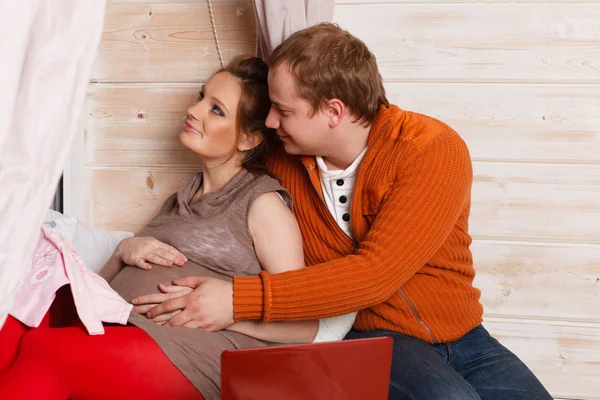 Lycklig Gravid Familj Med Barnkläder Sitta Soffa Huset — Stockfoto