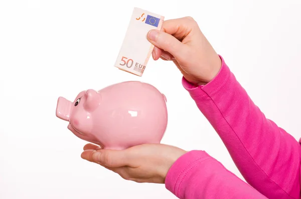 女性の手はピンクの貯金箱にユーロ紙幣を入れ — ストック写真