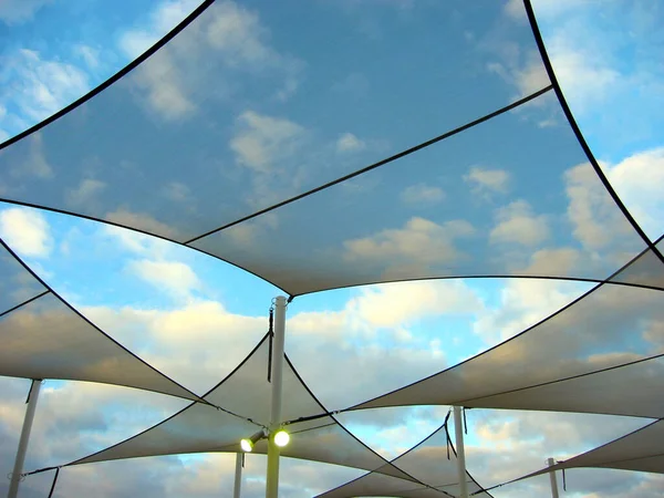 A set of modern shade sails on a cloudy day.