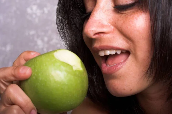 Mujer Joven Con Pelo Oscuro Mordiendo Una Manzana —  Fotos de Stock