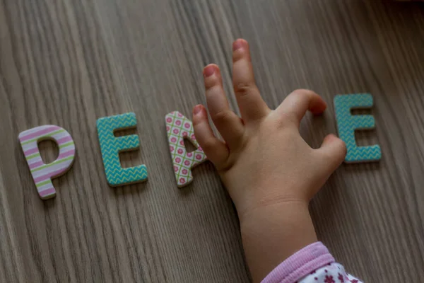 Kind Schrijft Woord Vrede Met Kleurrijke Speelgoedbrieven Een Houten Ondergrond — Stockfoto