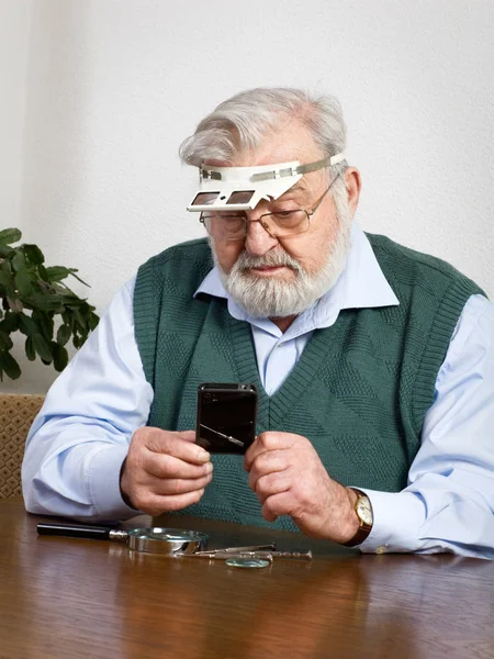 Homem Sênior Assistindo Seu Novo Telefone Celular Sob Loupe — Fotografia de Stock