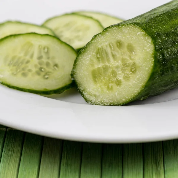 Een Verse Gesneden Komkommer Een Witte Plaat Bamboe — Stockfoto