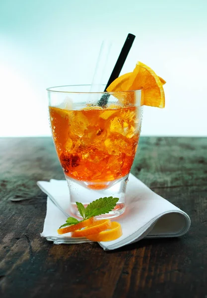 ラム酒とオレンジのカクテルのカラフルなガラスは 古い木製のバーカウンターに立って新鮮な果物 リンドとミントの葉で飾られています — ストック写真