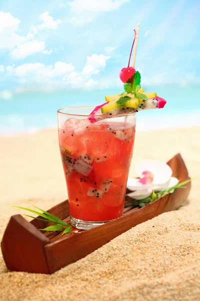 日当たりの良いビーチで新鮮な冷たいトロピカルフルーツカクテルのグラス クローズアップ — ストック写真