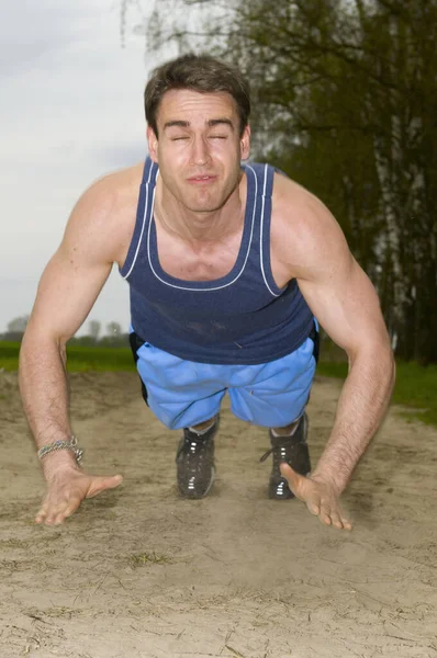 真っ青なスポーツウェアを着た男が砂の道の上に立っている姿を正面から撮影しました — ストック写真