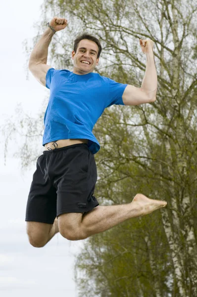 青いTシャツの若い男と砂の道で空気ジャンプと短い黒のスポーツパンツの冷凍フル長さ — ストック写真