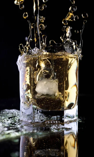 黒を背景にウイスキーのグラス ガラスの中のウィスキーのスプラッシュ ウイスキーと氷 — ストック写真