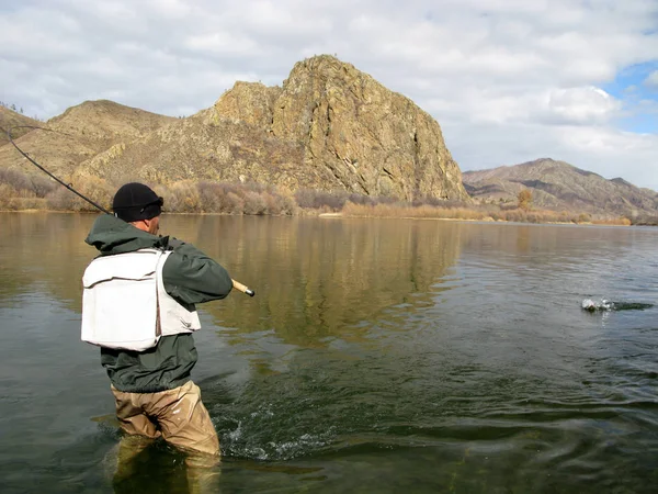背着背包在湖上钓鱼的男人 — 图库照片