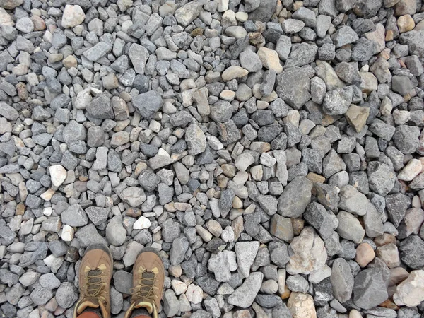 从上往下在砾石上穿的一双远足靴的水平射击 — 图库照片