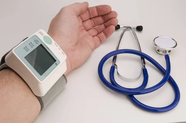 白い背景に血圧計と聴診器を付けた男性前腕 — ストック写真