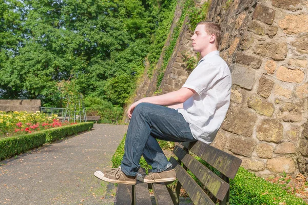 年轻人坐在长椅上晒太阳 — 图库照片