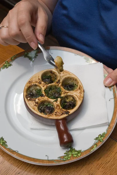 stock image plate with baked snail, piece of bread with a fork, diped it in the oil