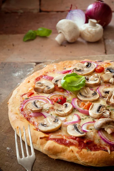 stock image Delicious crisp crusty vegetarian pizza topped with mushrooms, onion, tomato and melted cheese on old weathered bricks with copyspace