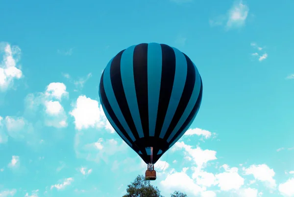 青と黒の縞模様の熱気球が青空に向かって上昇 — ストック写真
