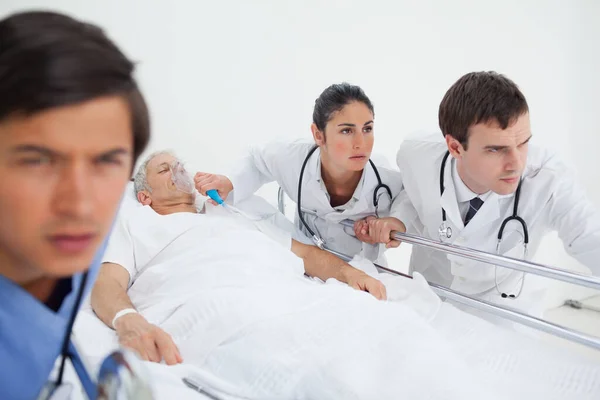 Два Лікарі Штовхають Всередину Лікарняне Ліжко Пацієнтом Оскільки Допомагає Медсестра — стокове фото