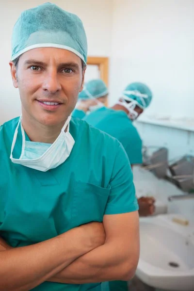 Smiling surgeon with his arms crossed in a hospital washroom