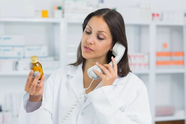 Γυναίκα Φαρμακοποιός Κρατώντας Ένα Μπουκάλι Χάπια Ενώ Στο Τηλέφωνο Ένα — Φωτογραφία Αρχείου