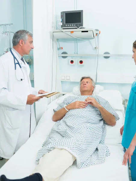 医者と看護師が病院のベッド病棟で患者と話してる — ストック写真