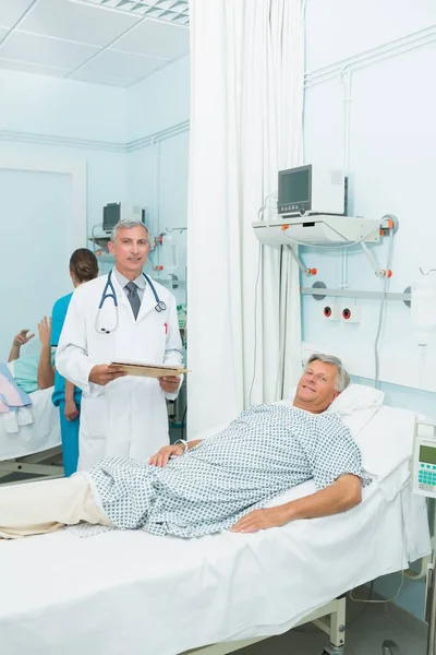 笑顔男性医師とともに幸せな男性患者でベッド病棟でA病院 — ストック写真