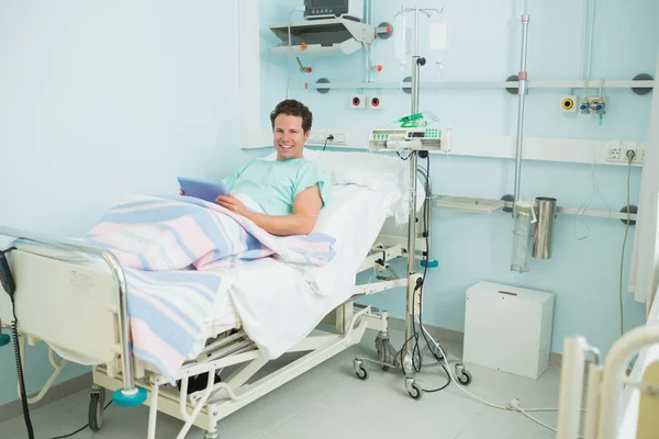 Чоловік Посміхається Тримаючи Тактильну Таблетку Лежачи Ліжку Лікарняному Палаті — стокове фото