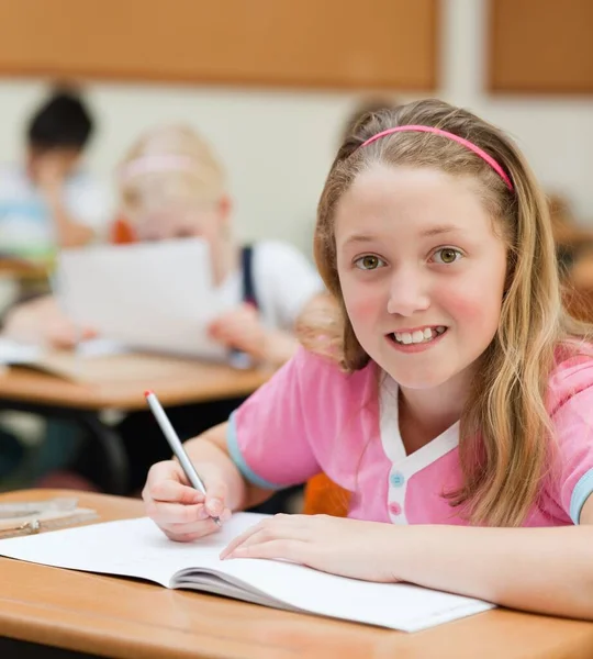 年幼的女学生坐在她的办公桌前 — 图库照片