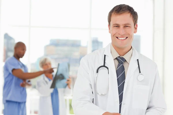 Médico Sonriente Con Colegas Detrás — Foto de Stock