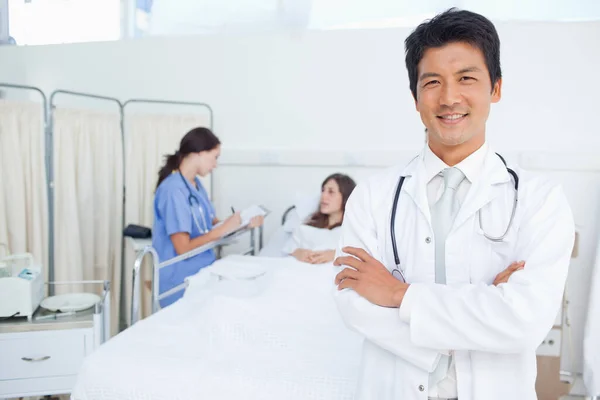 Doctor Cruza Los Brazos Mientras Una Enfermera Trata Paciente — Foto de Stock