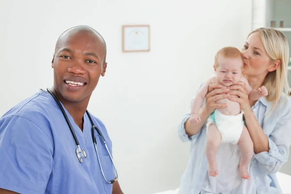 Glimlachende Dokter Met Moeder Haar Baby Naast Hem — Stockfoto