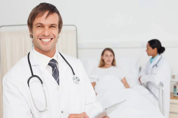 Χαμογελαστή Γιατρός Στέκεται Όρθια Μπροστά Από Έναν Ασθενή Και Ένα — Φωτογραφία Αρχείου