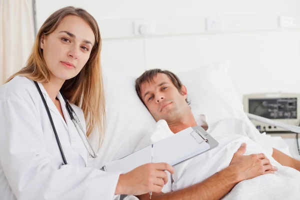 Ernsthafter Arzt Blickt Neben Einem Patienten Die Kamera — Stockfoto