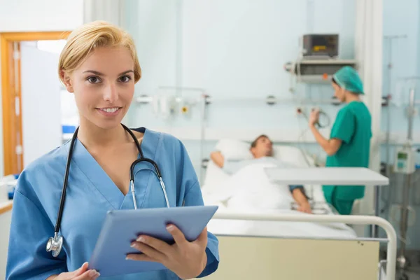 Ξανθιά Νοσοκόμα Κρατώντας Ένα Tablet Υπολογιστή Ενώ Χαμογελά Στο Θάλαμο — Φωτογραφία Αρχείου