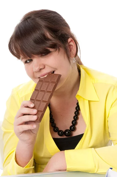 長い髪と黄色のブラウスを持つ10代の女の子は白を背景にしたチョコレートを楽しみながら食べました — ストック写真