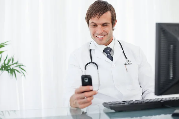 Médico Sonriente Mirando Teléfono Móvil —  Fotos de Stock