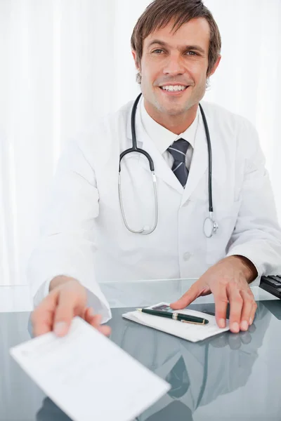 Usmívající Lékař Drží Předpis Zatímco Sedí Svého Stolu — Stock fotografie