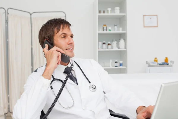 Zrelaksowany Lekarz Siedzi Przy Biurku Rozmawia Przez Telefon — Zdjęcie stockowe