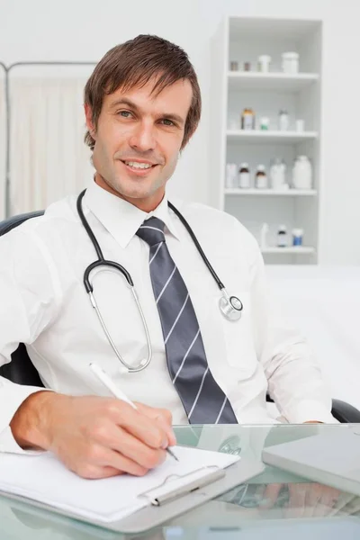 Smiling Doctor Looking Camera While Writing His Clipboard — Stock Photo, Image