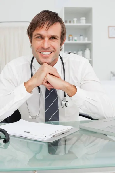 Doctor Colocando Sus Codos Escritorio Mientras Sonríe — Foto de Stock
