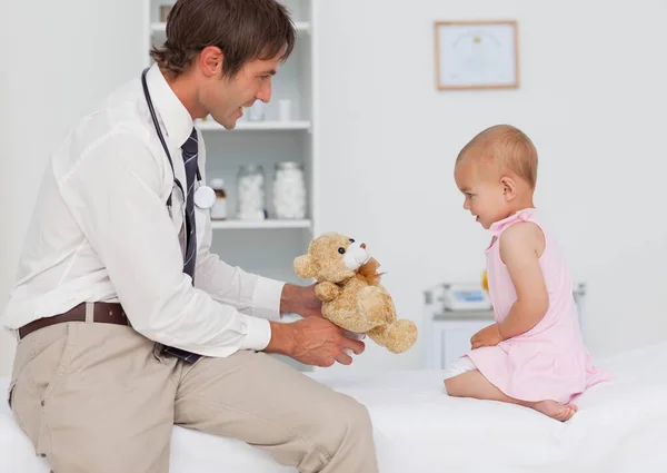 Médico Sonriente Que Ofrece Oso Peluche Bebé — Foto de Stock