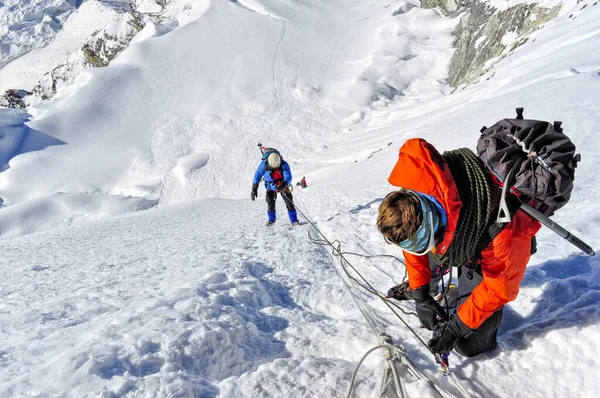 mountain guide ropes his guest on the summit flank of the island peak. nepal.