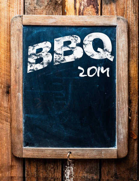Old grunge BBQ advertising sign on an old school slate board with a distressed wooden frame and copyspace for your text mounted on wooden boards