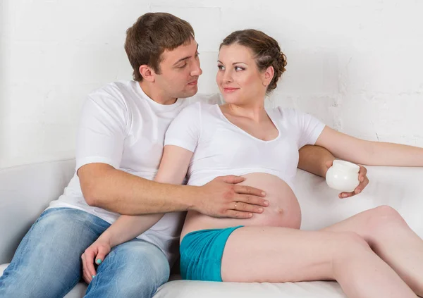 Ung Gravid Kvinna Och Hennes Man Med Kosmetisk Grädde Sitter — Stockfoto