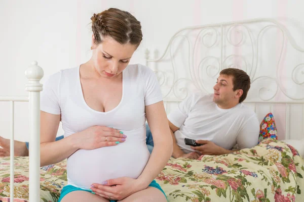 孕妇对躺在床上看电视的丈夫很生气 — 图库照片