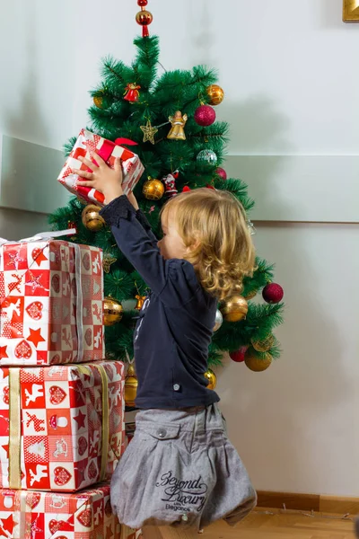 Klein Meisje Met Een Kerstcadeau Met Boom Achtergrond Thuis Stockfoto