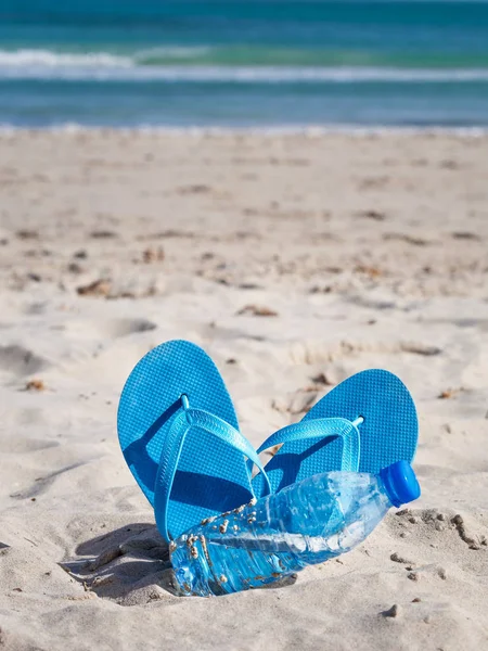 砂のビーチで青いフリップフロップと水のボトル — ストック写真