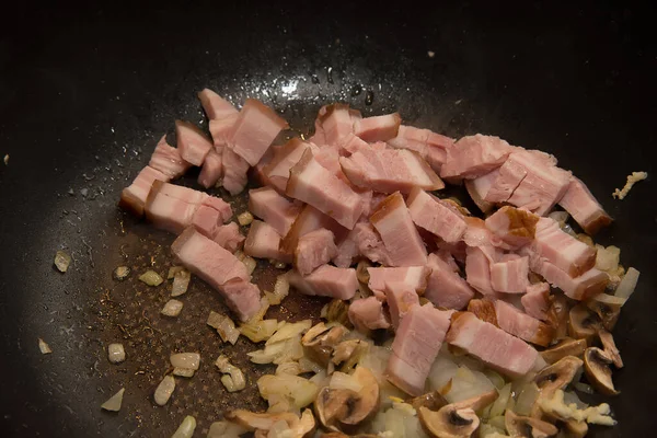 家庭でカルボナーラを調理するときあなたはみじん切り玉ねぎをローストする必要があります キノコとベーコン それらを熱心に混合 — ストック写真
