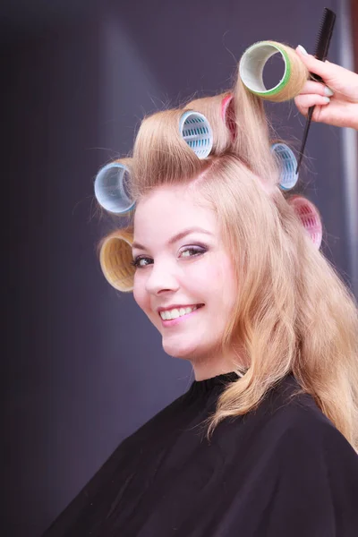 beautiful young woman in beauty salon. smiling blond girl with hair curlers rollers to hairdresser. hairstyle.