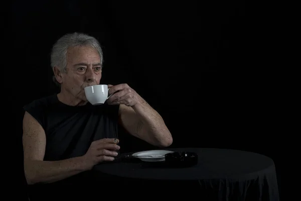 Anciano Sentado Mesa Bebiendo Café Fumando Cigarrillo —  Fotos de Stock