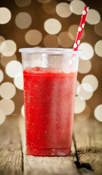 一杯美味的冷草莓软糖 配上红色波尔卡圆点稻草 背景是节日酒会上闪闪发光的灯光 — 图库照片