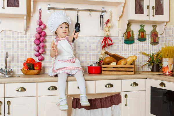 Little Girl Apron Cap Cook Sits Kitchen House Mother Helper — Stock Photo, Image